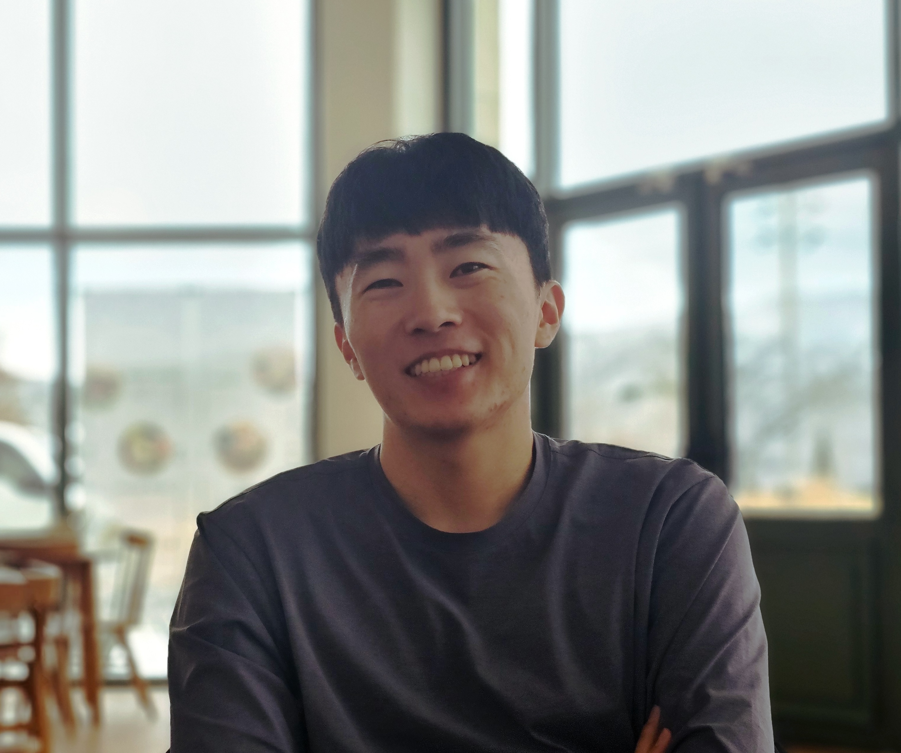 Junyong Park smiling in front of a window